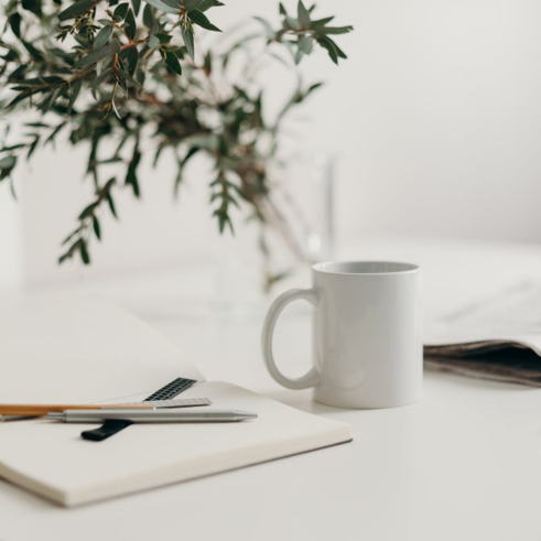 Coffee cup and a notebook with pens on a desk