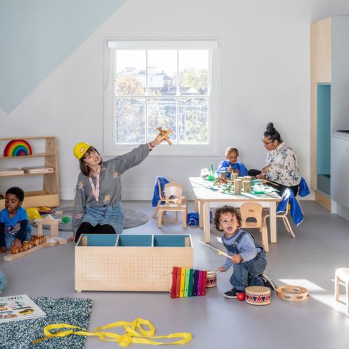 Educators playing with toys and entertaining children in a nursery setting