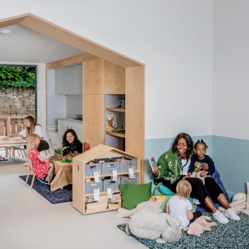 Nursery educators playing with children in a nursery playroom